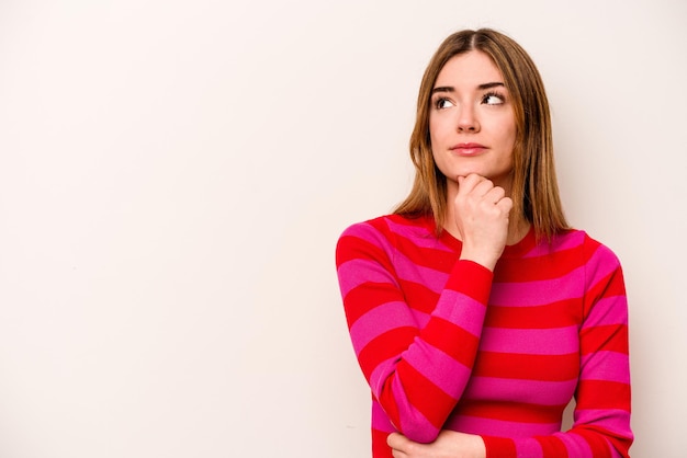 Jeune femme caucasienne isolée sur fond blanc regardant de côté avec une expression douteuse et sceptique