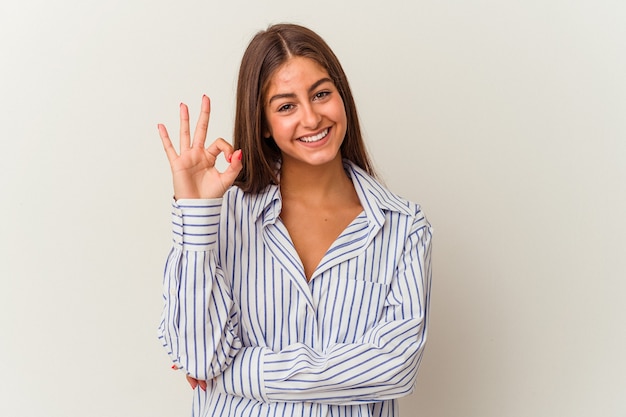 Jeune femme caucasienne isolée sur fond blanc rit et ferme les yeux, se sent détendue et heureuse.