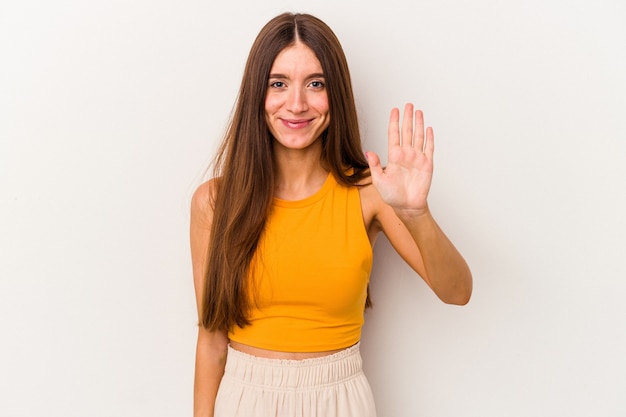 Jeune femme caucasienne isolée sur fond blanc souriant joyeux montrant le numéro cinq avec les doigts.