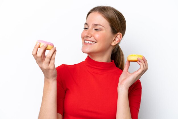 Jeune femme caucasienne isolée sur fond blanc tenant des beignets avec une expression heureuse