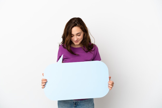 Jeune femme caucasienne isolée sur fond blanc tenant une bulle de dialogue vide