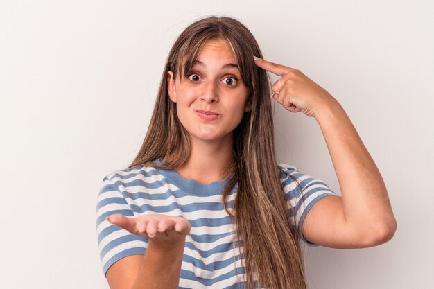 Jeune femme caucasienne isolée sur fond blanc tenant et montrant un produit à portée de main.