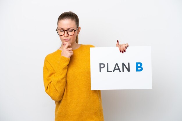 Jeune femme caucasienne isolée sur fond blanc tenant une pancarte avec le message PLAN B et pensant