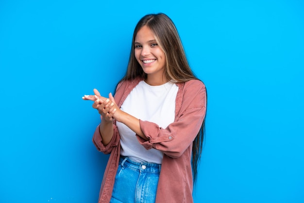 Jeune femme caucasienne isolée sur fond bleu applaudissant