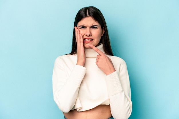 Jeune femme caucasienne isolée sur fond bleu ayant une forte douleur aux dents douleur molaire