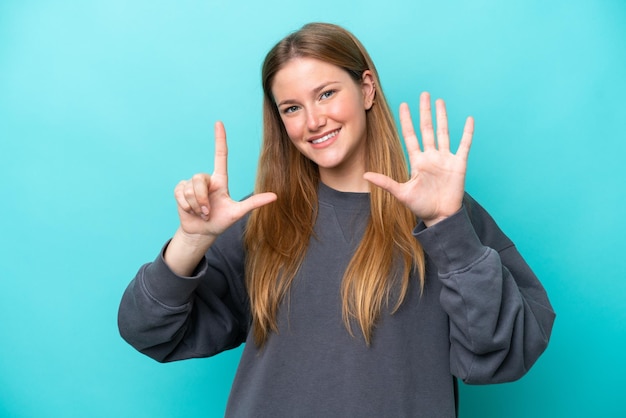 Jeune femme caucasienne isolée sur fond bleu comptant sept avec les doigts