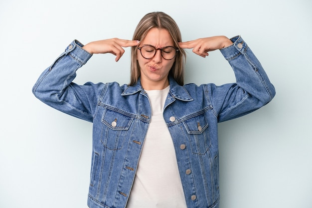 Jeune femme caucasienne isolée sur fond bleu concentrée sur une tâche, gardant les index pointant la tête.