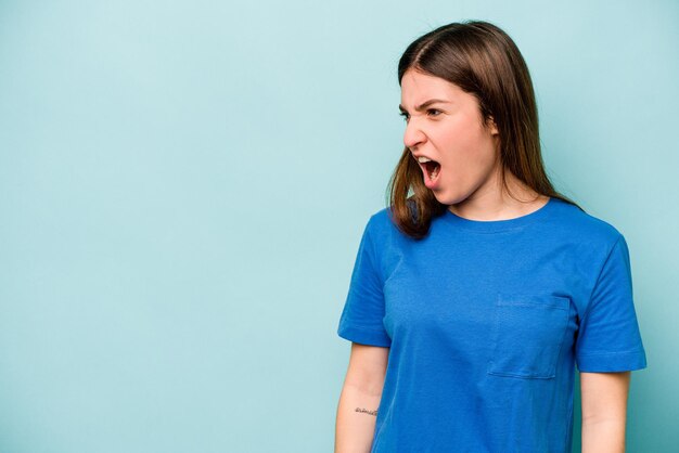 Jeune femme caucasienne isolée sur fond bleu criant un concept de rage très en colère frustré