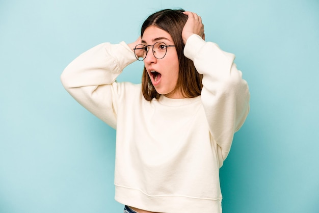 Jeune femme caucasienne isolée sur fond bleu criant très excitée passionnée satisfaite de quelque chose