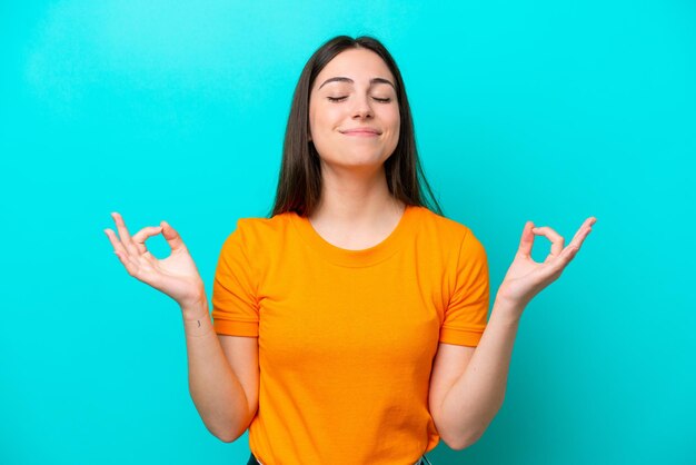 Jeune femme caucasienne isolée sur fond bleu dans une pose zen