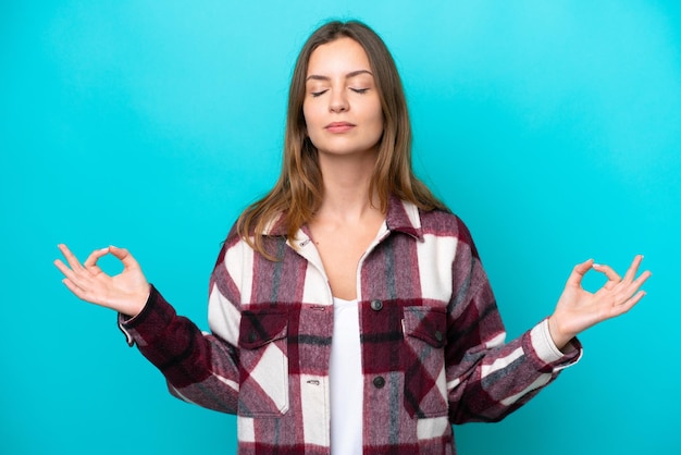 Jeune femme caucasienne isolée sur fond bleu dans une pose zen