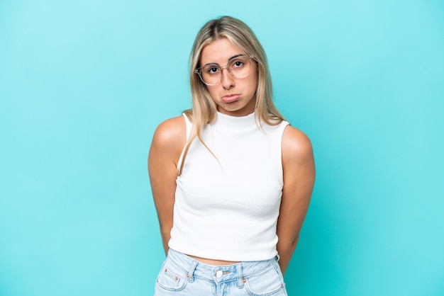 Jeune femme caucasienne isolée sur fond bleu avec une expression triste