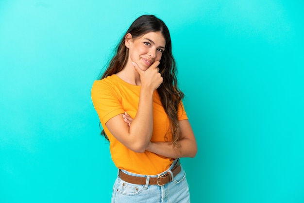 Jeune femme caucasienne isolée sur fond bleu heureux et souriant