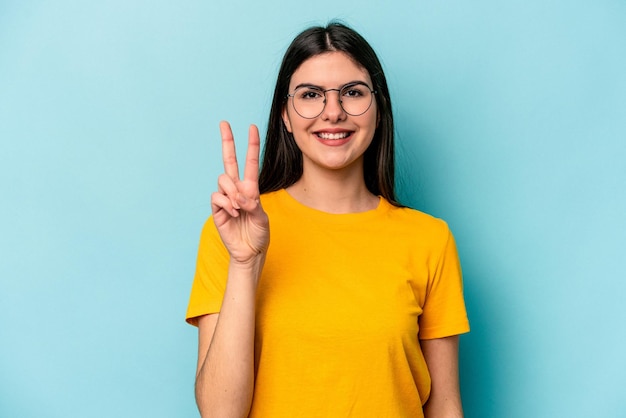 Jeune femme caucasienne isolée sur fond bleu joyeuse et insouciante montrant un symbole de paix avec les doigts