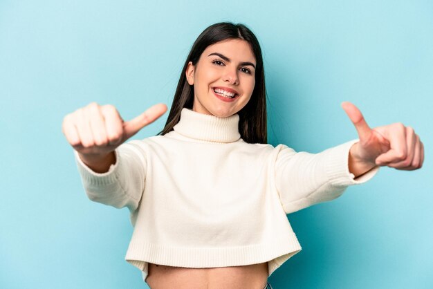 Jeune femme caucasienne isolée sur fond bleu levant les deux pouces vers le haut souriant et confiant