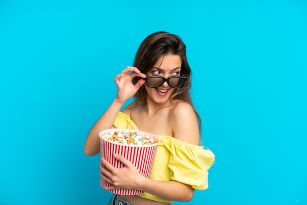 Jeune Femme Caucasienne Isolée Sur Fond Bleu Avec Des Lunettes 3d Et Tenant Un Grand Seau De Pop-corn