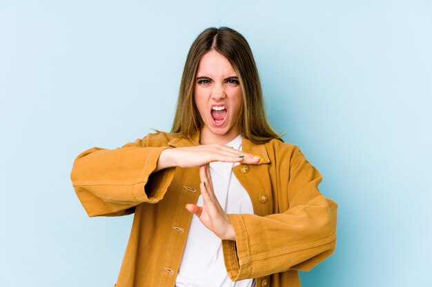 Jeune femme caucasienne isolée sur fond bleu montrant un geste de timeout.