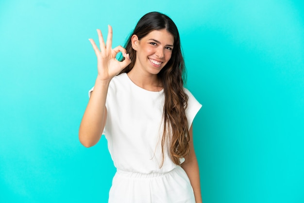 Jeune femme caucasienne isolée sur fond bleu montrant un signe ok avec les doigts