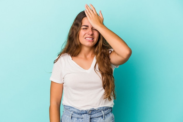 Jeune femme caucasienne isolée sur fond bleu oubliant quelque chose, frappant le front avec la paume et fermant les yeux.