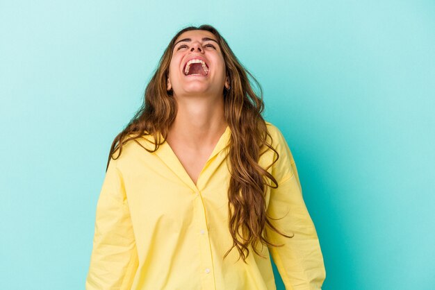 Jeune femme caucasienne isolée sur fond bleu riant détendue et heureuse, cou tendu montrant les dents.