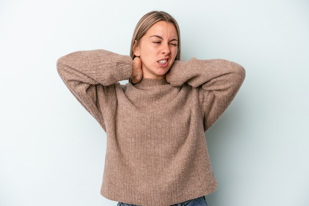 Jeune femme caucasienne isolée sur fond bleu souffrant de douleurs au cou en raison d'un mode de vie sédentaire.