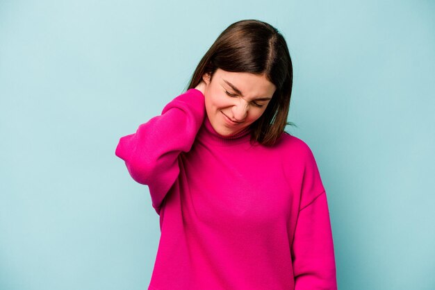 Jeune femme caucasienne isolée sur fond bleu souffrant de douleurs au cou en raison d'un mode de vie sédentaire