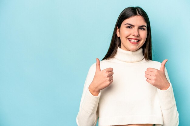 Jeune femme caucasienne isolée sur fond bleu souriant et levant le pouce vers le haut