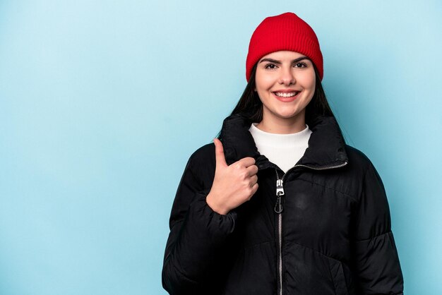 Jeune femme caucasienne isolée sur fond bleu souriant et levant le pouce vers le haut