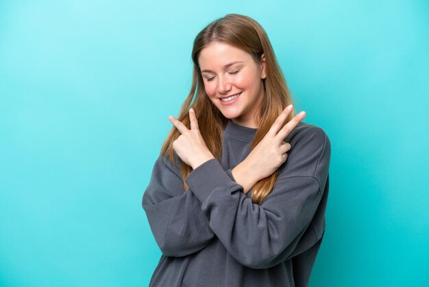 Jeune femme caucasienne isolée sur fond bleu souriant et montrant le signe de la victoire