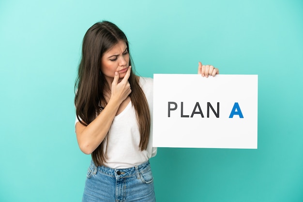 Jeune femme caucasienne isolée sur fond bleu tenant une pancarte avec le message PLAN A et pensant