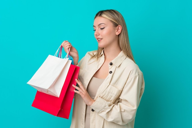 Jeune femme caucasienne isolée sur fond bleu tenant des sacs à provisions