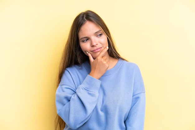 Jeune femme caucasienne isolée sur fond jaune ayant des doutes