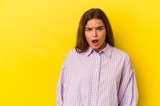 Jeune femme caucasienne isolée sur fond jaune choquée à cause de quelque chose qu'elle a vu.