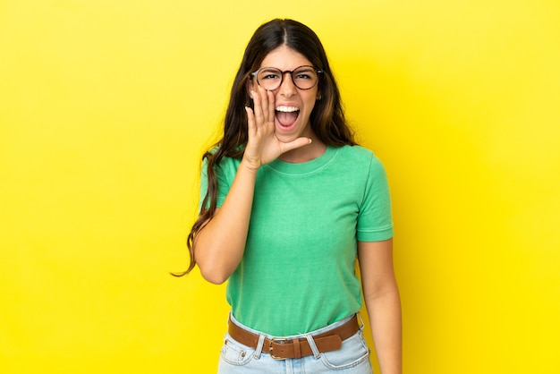 Jeune femme caucasienne isolée sur fond jaune criant avec la bouche grande ouverte