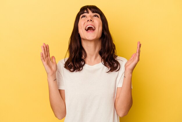 Jeune femme caucasienne isolée sur fond jaune éclate de rire en gardant la main sur la poitrine.