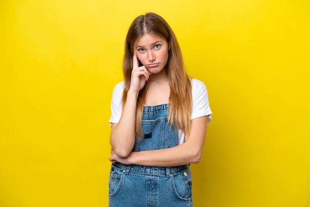 Jeune femme caucasienne isolée sur fond jaune pensant une idée