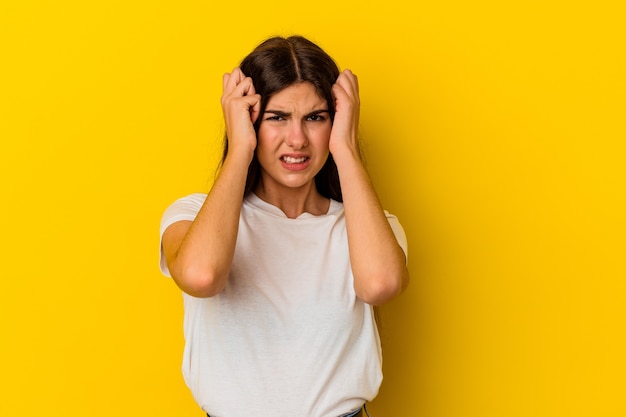 Jeune femme caucasienne isolée sur fond jaune pleurant, mécontente de quelque chose, concept d'agonie et de confusion.