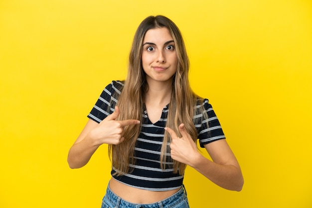 Jeune femme caucasienne isolée sur fond jaune pointant vers soi