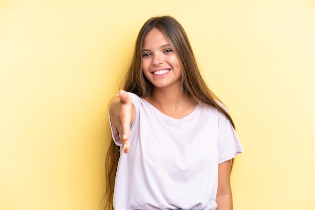 Jeune femme caucasienne isolée sur fond jaune se serrant la main pour conclure une bonne affaire