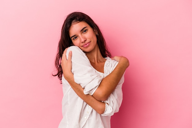 Jeune femme caucasienne isolée sur fond rose câlins, souriante insouciante et heureuse.