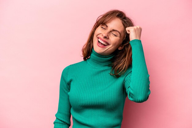 Jeune femme caucasienne isolée sur fond rose célébrant une victoire passion et enthousiasme expression heureuse