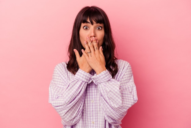 Jeune femme caucasienne isolée sur fond rose choquée, couvrant la bouche avec les mains, impatiente de découvrir quelque chose de nouveau.