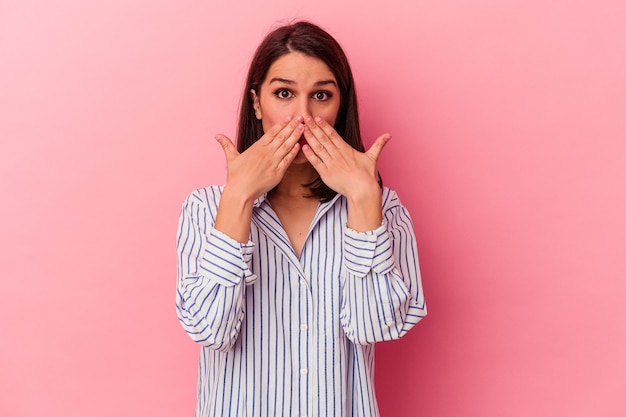 Jeune femme caucasienne isolée sur fond rose choquée couvrant la bouche avec les mains.