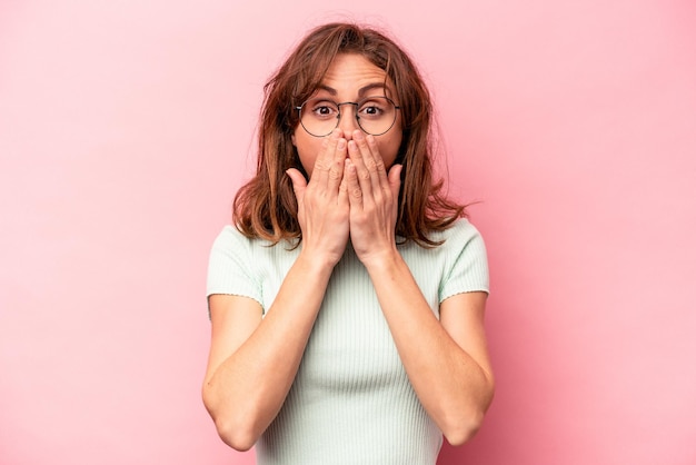 Jeune femme caucasienne isolée sur fond rose choquée couvrant la bouche avec les mains