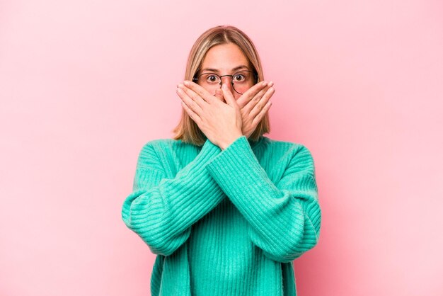 Jeune femme caucasienne isolée sur fond rose choquée couvrant la bouche avec les mains