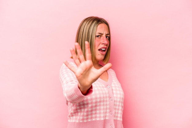 Jeune femme caucasienne isolée sur fond rose choquée en raison d'un danger imminent