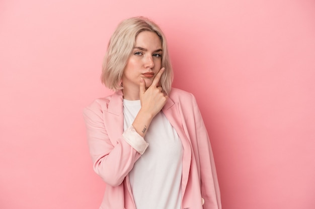 Jeune femme caucasienne isolée sur fond rose contemplant, planifiant une stratégie, réfléchissant à la manière d'une entreprise.