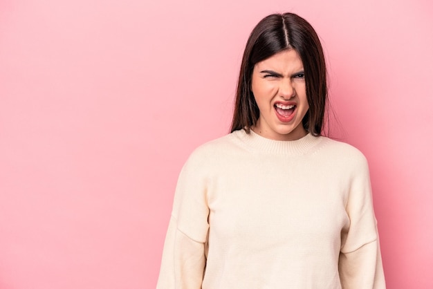 Jeune femme caucasienne isolée sur fond rose criant un concept de rage très en colère frustré