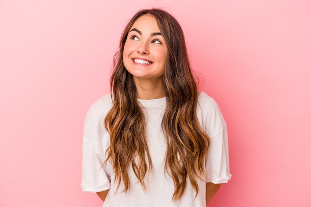 Jeune femme caucasienne isolée sur fond rose détendue et joyeuse en riant, le cou étiré montrant les dents.