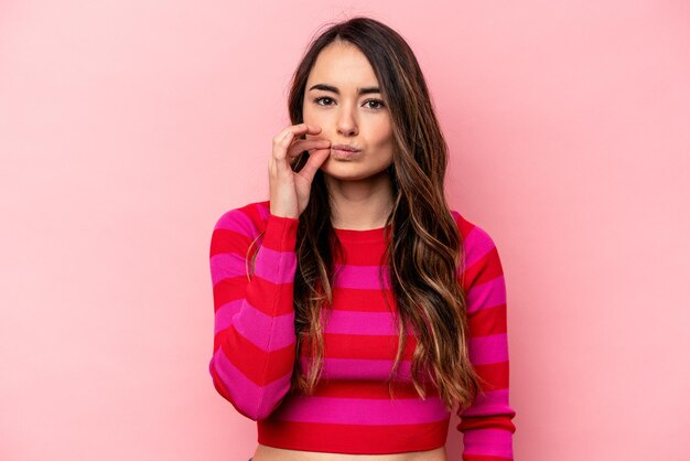 Jeune femme caucasienne isolée sur fond rose avec les doigts sur les lèvres en gardant un secret